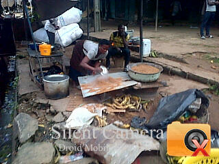 Woman drying sawdust on live-coal. Afubera Street, Onitsha, Nigeria. photo Okoye Chukwudi Charles